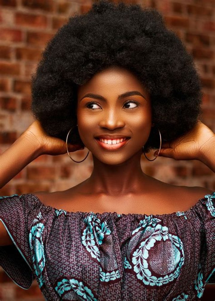 a woman with an afro standing in front of a wall